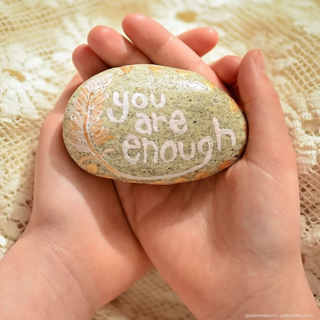 you are enough hand painted stone being held in hands